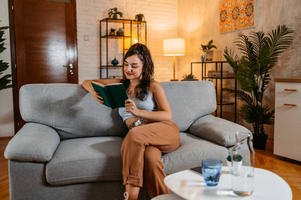 istock Young Woman Sitting On The Sofa And Reading A Book 1438632232