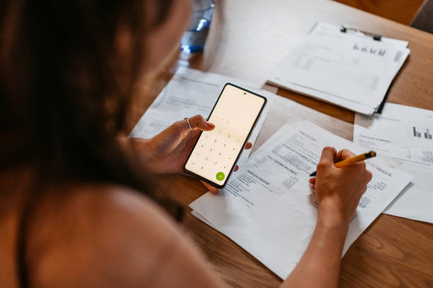 istock Young Woman Checking Her Finances Using Smart Phone At Home 1438634388