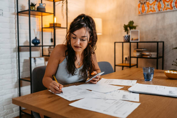 istock Young Woman Checking Her Finances Using Smart Phone At Home 1438634538