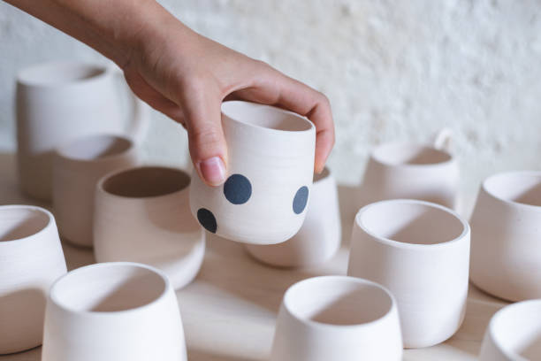 Three white ceramic mugs with green, yellow and blue dots isolated on a white background. Cup for hot drinks.