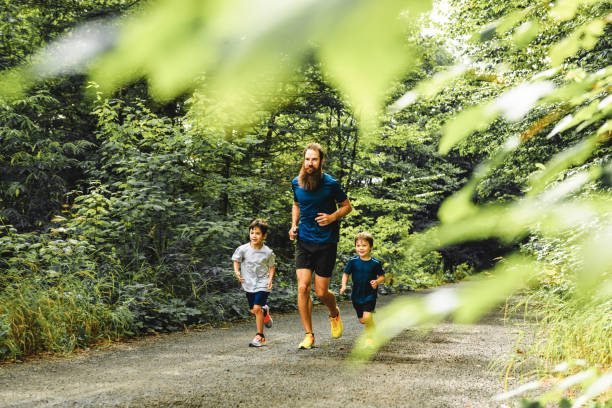 istock father and two sons running outside in forest 1438635225