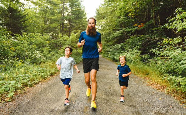 istock father and two sons running outside in forest 1438635228