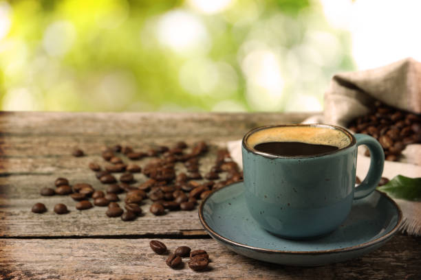istock Cup of aromatic hot coffee and beans on wooden table outdoors. Space for text 1438636785