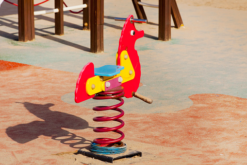 Seesaw in red duck shape, children outdoors playground toy. Soft cork flooring. Galicia, Spain.