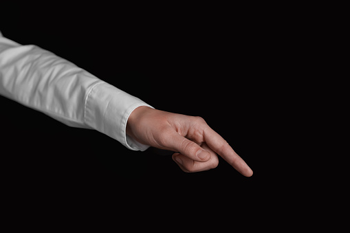 Businesswoman pointing at something on black background, closeup