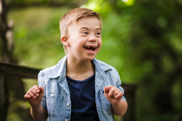 porträt eines kleinen jungen mit down-syndrom beim spielen in einem park - cute little boys caucasian child stock-fotos und bilder