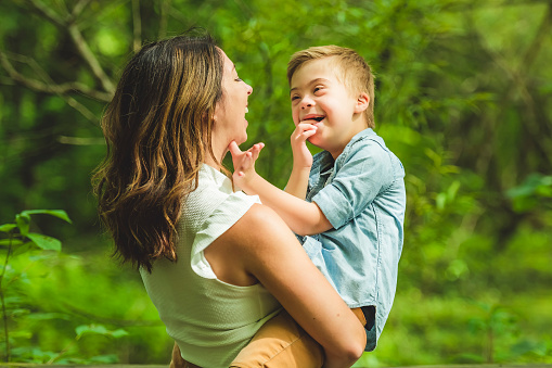 A Portrait of a little boy with down syndrome while playing in a park with his mother