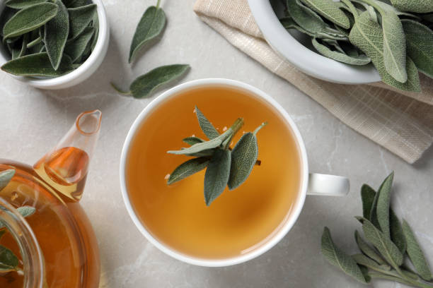 istock Flat lay composition with cup of sage tea and green leaves on light grey table 1438641020