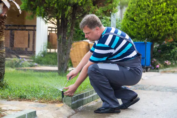 Male gardener repairing lawn irrigation system.,