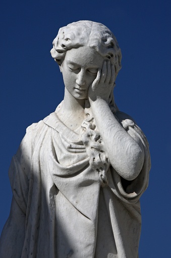 A low angle shot of a statue of a woman under a blue sky