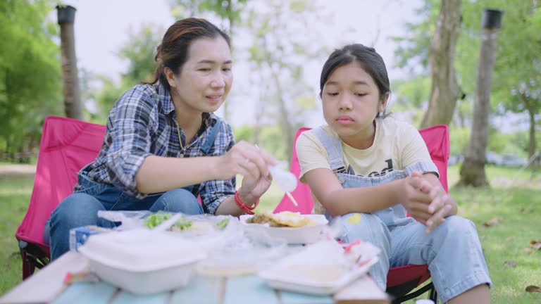 Mother and daughter Have a meal together while camping.