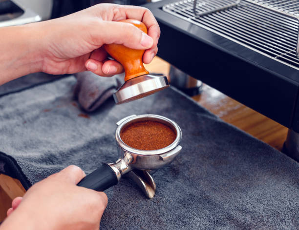 istock Barista cafe making coffee with manual presses ground coffee using tamper on the wooden counter bar at the coffee shop 1438653614