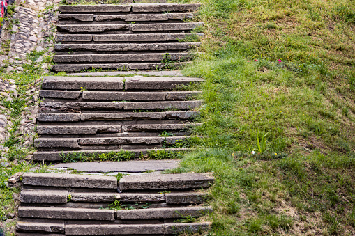 Old concrete stairs with cracks next to a grass hill
