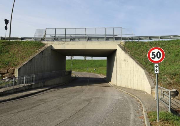 istock Speed limit sign in front of a concrete road underpass with sidewalks on both sides. 1438655398