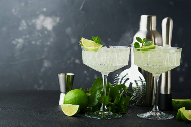 istock Margarita cocktail with lime, tequila, mint and ice on dark table with amazing backlight, copy space. Classic Margarita or Daiquiry Cocktail. Bar card or counter concept. Selective or soft focus. 1438656430