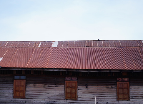 A low angle view of an old brown wooden building with wooden windows