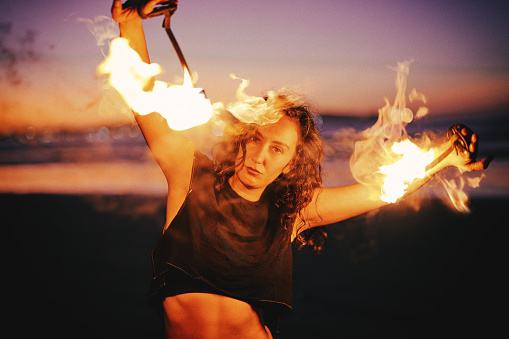 latin young woman does performance with fire on the beach at night portrait