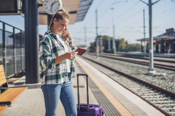 Confused woman with ticket on a train station Confused woman looking at her ticket while standing on a train station. train ticket check stock pictures, royalty-free photos & images