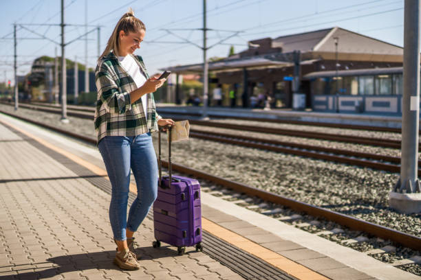 istock Woman using mobile phone and holding map on a train station 1438660139