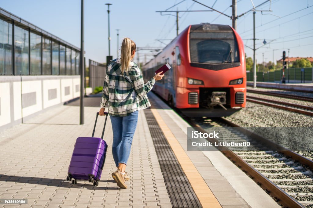 Woman waiting to  enter  into the train on station Woman with suitcase holding ticket and waiting to  enter  into the train on station. Station Stock Photo