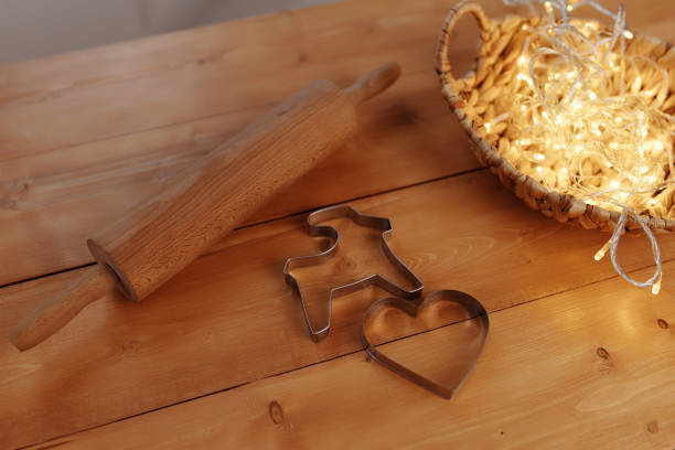 We make gingerbread and cookies with our own hands for Valentine's Day and Christmas. On a wooden table, a rolling pin is a mold in the shape of a heart.