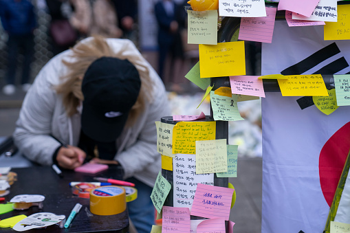 Seoul, South Korea - November 3, 2022: A woman writes a message on an adhesive note, follow a deadly stampede involving Halloween revellers in Itaewon district.