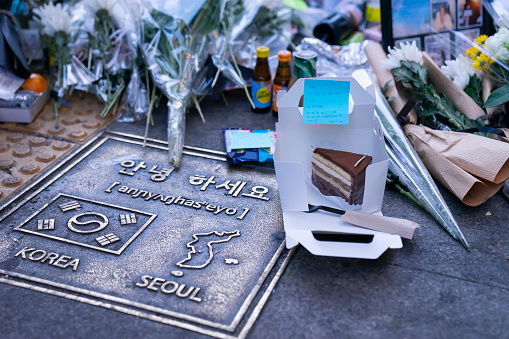 Seoul, South Korea - November 3, 2022: A cake is left beside flowers at a makeshift memorial outside Itaewon subway station, in the aftermath of a human crush involving Halloween revellers.