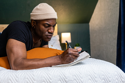 Young black male spending time in his room journaling as a form of self care