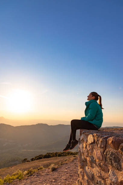 istock Beautiful woman sitting on an edge during sunset with mountains 1438665464