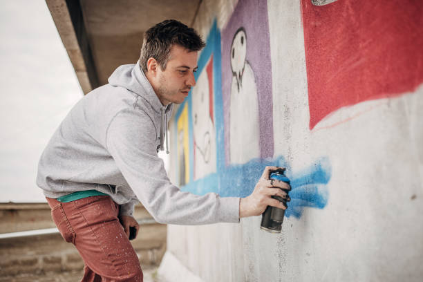 istock Man painting graffiti on wall 1438669276