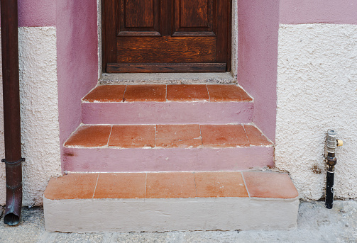 Tidy and clean doorsteps painted in pink, with terracotta tiles