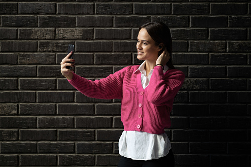 Beautifull business woman using phone outdoors
Standing by the brick wall
Taking selfies
Copy space
