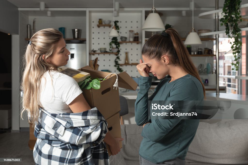 Young lesbian couple having argue and relationship breakup one woman throwing out her girlfriend with her stuff in the boxes showing her the door. LGBTQ+ end of the relationship by moving out. Couple - Relationship Stock Photo