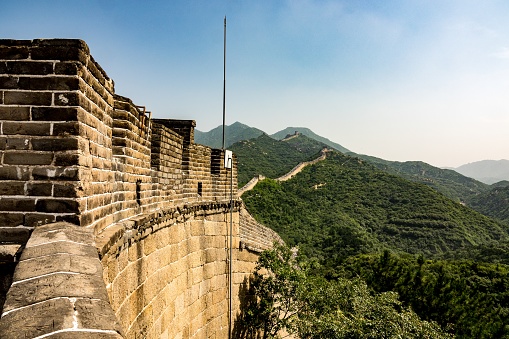 A high angle closeup shot of the famous Great Wall of China surrounded by green trees in summer