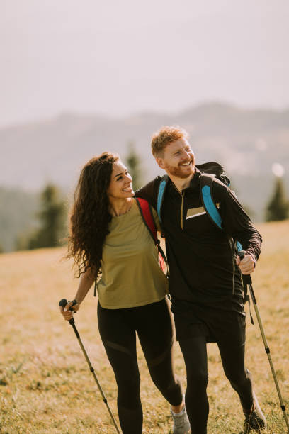 istock Smiling couple walking with backpacks over green hills 1438677360