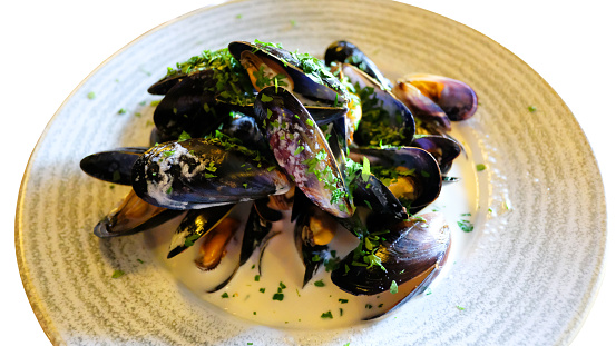 Full plate of moulds mariner or mussels in a cream and wine sauce, garnished with fresh parsley.