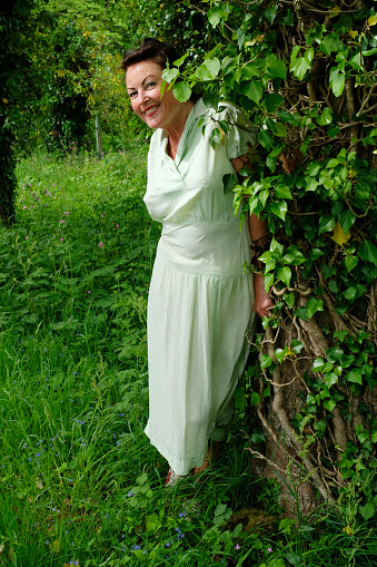 Attractive mature female looking at camera wearing a full length green dress