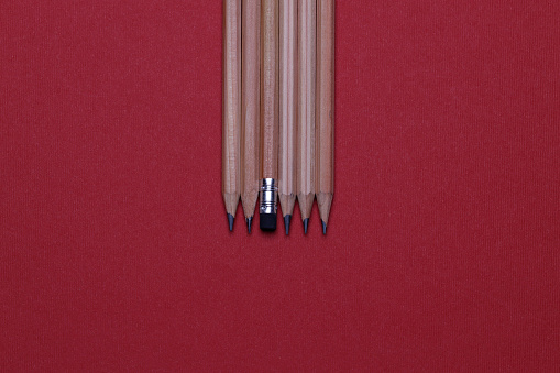 Close up of a yellow pencil tip and sharpener on white background. The pencil is on foreground with a sharp tip and the shiny metal pencil sharpener is on background.