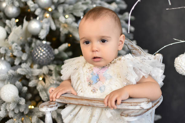 istock Baby 1 year old  sitting in chair with Christmas tree 1438683280