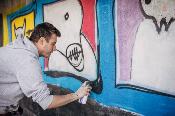 istock Man painting graffiti on wall 1438684044