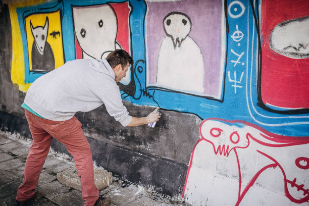 istock Man painting graffiti on wall 1438684247