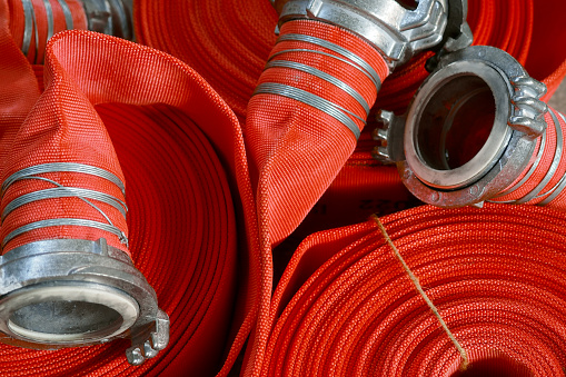 View of many twisted red fire hoses close-up in full screen. New fire extinguishing equipment. Background..