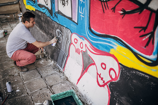 bologna,Italy-June 7,2014:young artist painting a wall in the middle of the day