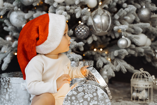 Portrait of a Adorable baby  in Santa hat with a gift on a Christmas  background.