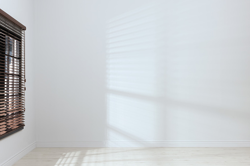 Empty room with white walls, large window and wooden floor