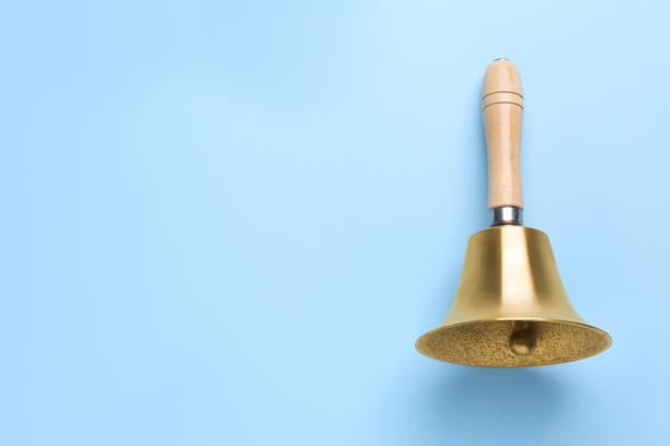 Golden school bell with wooden handle on light blue background, top view. Space for text Golden school bell with wooden handle on light blue background, top view. Space for text school handbell stock pictures, royalty-free photos & images