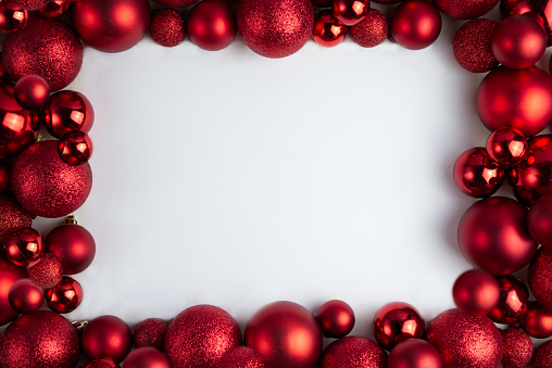 Framing of red Christmas balls of different sizes and textures on a white background, copy space