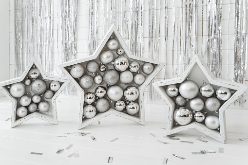 Festive background, Three silver stars filled with Christmas balls on the background of a wall of tinsel