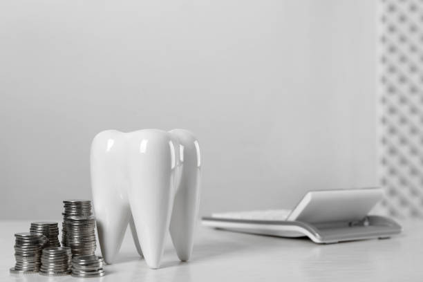 istock Ceramic model of tooth, coins and calculator on white table, space for text. Expensive treatment 1438692004