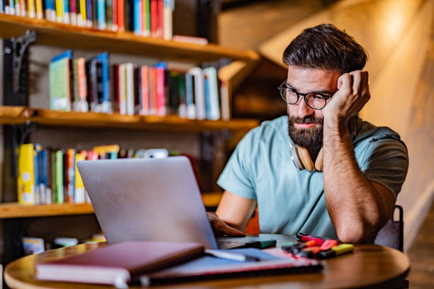 istock Male student using laptop in the library 1438692216
